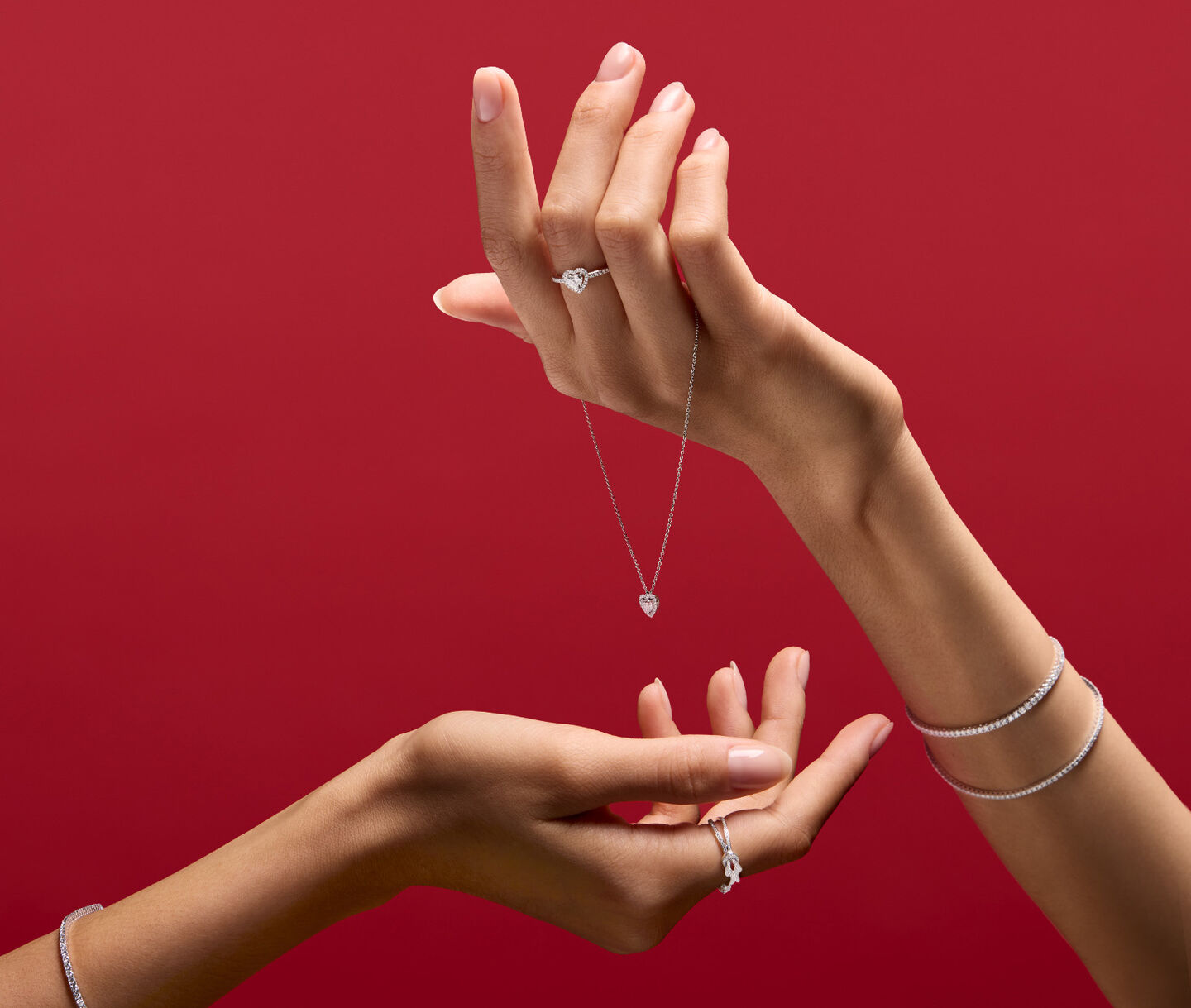 A woman holding Maison Birks jewellery on red background.